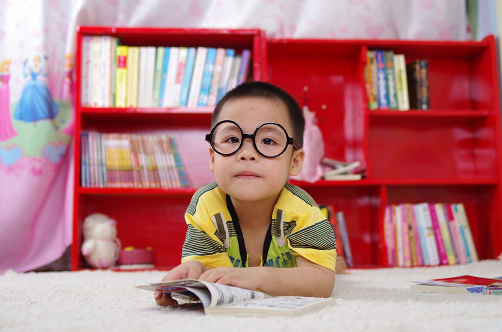 Child wearing glasses and reading a book